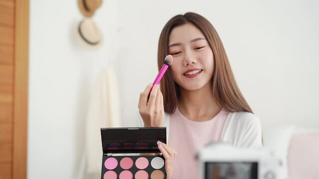 Young beautiful Asian woman professional beauty vlogger influencer recording make up tutorial video clip for social media marketing