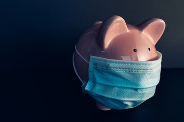 Global economy during coronavirus pandemic. Piggy bank wearing surgical face mask. Financial crisis, banking concept.