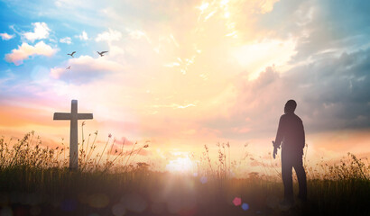 Easter Religious concept: Silhouette christian over cross meadow sunset background