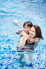 Scared little girl hugging mother as she is afraid of swimming in pool