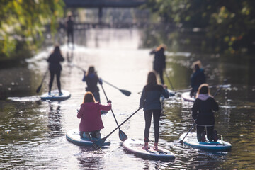 Group of sup surfers stand up paddle board, women stand up paddling together in the city river and canal