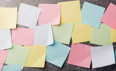 Many blank multicolored paper stick note list on concrete wall background, Business reminder memory...
