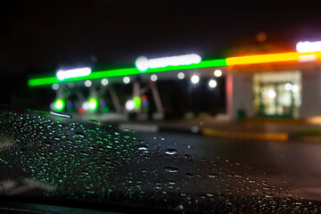 Night gas station on the background of glass in the car with rain on the window.