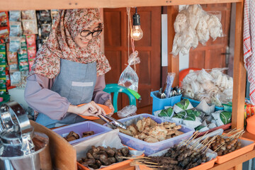 hijab young woman selling the cart shop smiles when serving customers at the cart stall