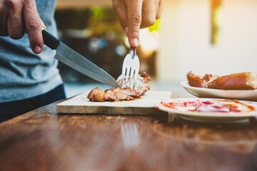 Chefs use a knife to cut steaks to thinly slices to prepare meals at outdoor parties.
