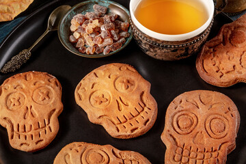 Halloween ginger cookies in the shape of skulls, homemade Dia de los muertos biscuits on a dark wooden background