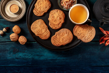 Halloween ginger cookies in the shape of skulls, homemade Dia de los muertos biscuits, shot from above witch copy space on a dark wooden background