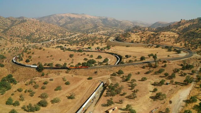 Aerial view of long freight train passing through Tehachapi Loop, California