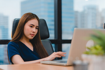 Successful beautiful executive Asia young businesswoman smart casual wear watching tutorial about creative ideas at laptop computer during working process in modern office workplace.