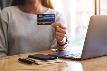 Closeup image of a woman holding credit cards while using laptop computer in office
