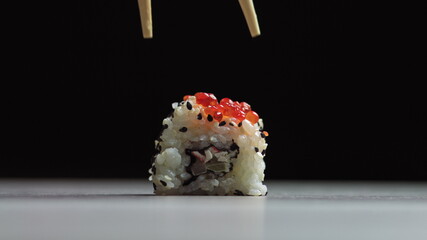 Chef cutting rolls of sushi with a knife on a stone board. - shot at a low angle. Beautiful female...