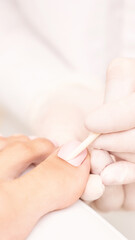 Beautiful salon procedure with pink pedicure on towel background. For decoration design. Healthcare. Woman body care. Spa treatment. White background. Nail polish. Apricot stick prepare