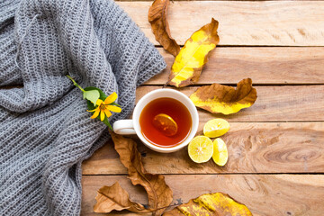  herbal healthy drinks hot lemon tea for health care cough sore with flowers ,yellow leaves and knitting wool scarf of lifestyle in autumn season arrangement flat lay style on background wooden