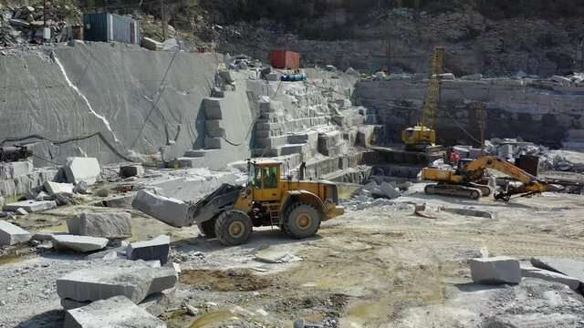Bulldozer works on a marble quarry, loads a stone into a bucket