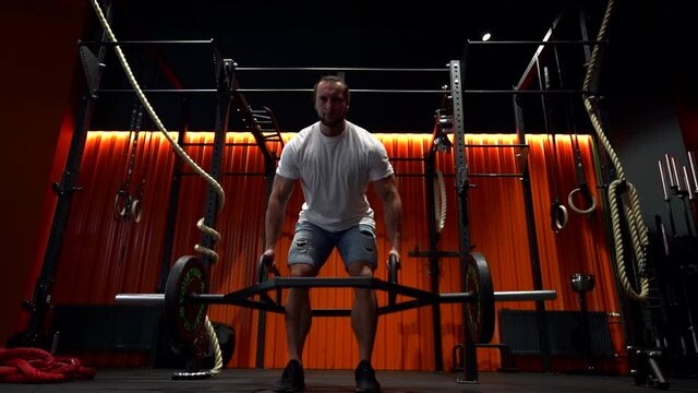 powerlifter is lifting rod with weights in gym, strongman and bodybuilder is training alone in fitness club