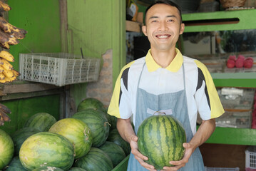 Fototapeta premium Shop waitress boy in apron carry watermelon at fruit stand, fresh fruit concept