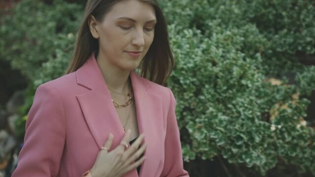 A Young Professional Caucasian Woman In Pink Blazer Walking Down The Street Pavement - Tracking Shot (Slow Motion)