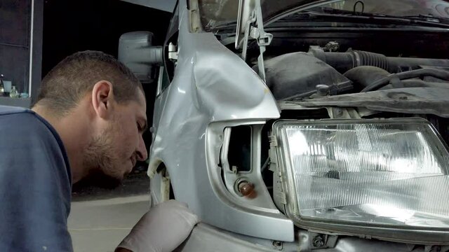 Repair Man in service station working on fender and bumper after car damage.Dolly closeup shot.
