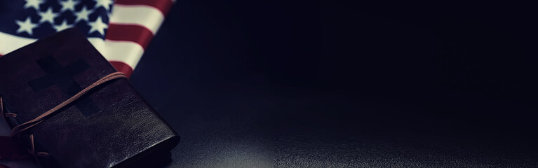 American flag and holy bible book on a mirror background. Symbol of the United States and religion. Bible and striped flag on a black background.