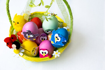 Easter eggs in pastel colors with a decor in the form of birds lie in a beautiful green basket, copy space