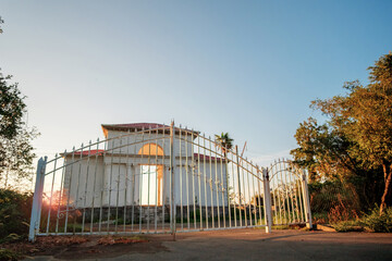 Fototapeta premium Abandoned building with closed rusty white metal gate and
