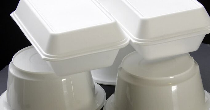 Top view Close up of Styrofoam takeaway boxes, white foam boxes, rectangular shaped clamshell style container with an attached lid, on black background.