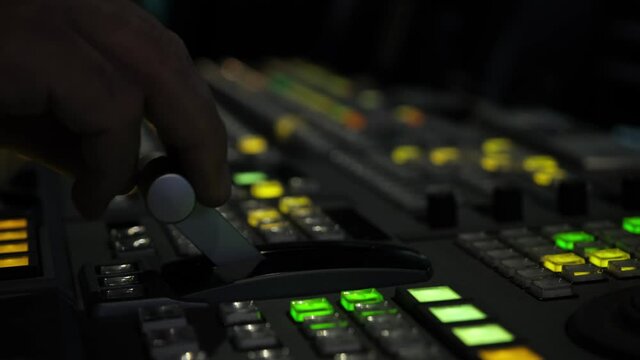 Television director is moving handle on a control panel during tv filming in studio