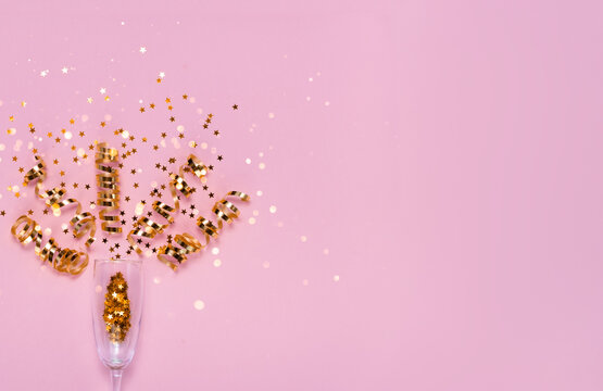 Champagne glass with ribbons and christmass confetti decorations. Festive holiday concept. Top horizontal view copyspace