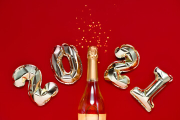 Golden foil balloons 2021 with a bag on festive red background with bokeh. Top horizontal view copyspace. New year and Christmas shopping concept.