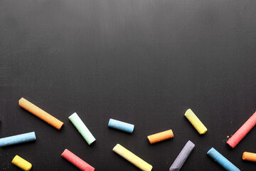 Pieces of colorful chalk on blackboard, top view