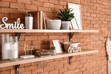Wooden shelves with stylish decor hanging on wall in room