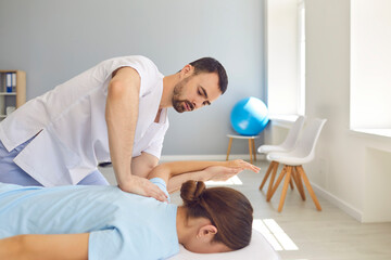 Young doctor specialist curing client's back and shoulders in modern health center - obrazy, fototapety, plakaty