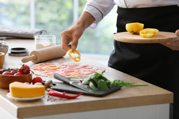 Mature male chef cooking tasty pizza in kitchen, closeup