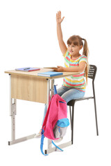 Little pupil with raised hand sitting at school desk against white background