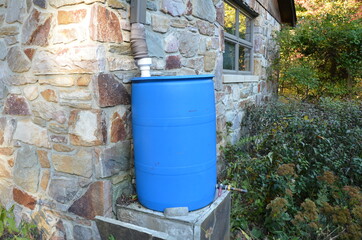 blue rain barrel with downspout and stone building
