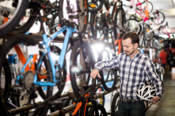 Fototapeta na wymiar Man considers bicycle handlebar in store when choosing bike