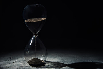 Hourglass on dark background, closeup. Urgency and running out of time concept