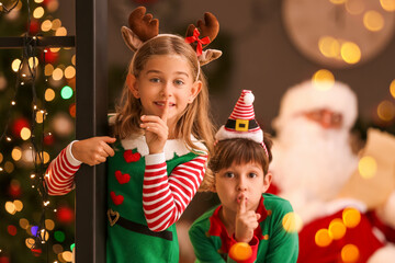 Cute little elves showing silence gesture at home on Christmas eve