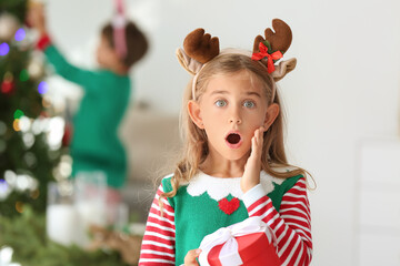 Surprised little elf with gift at home on Christmas eve