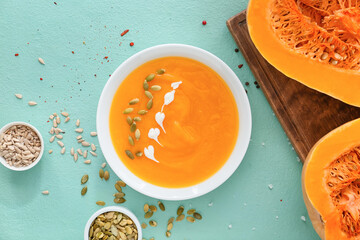 Tasty pumpkin cream soup in bowl on color background