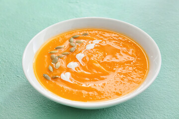 Tasty pumpkin cream soup in bowl on color background