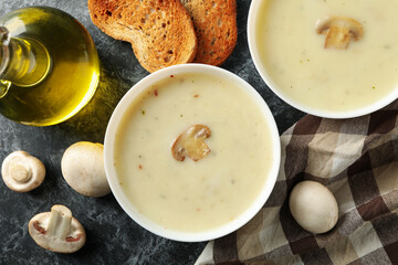 Concept of tasty lunch with bowls of mushroom soup on black smoky background