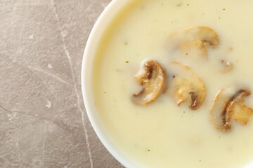 Bowl of tasty mushroom soup on gray background