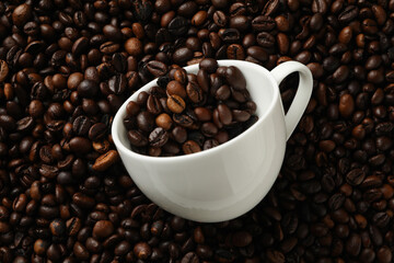 White cup on coffee beans background, close up