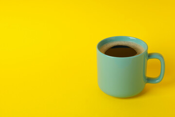 Cup of coffee on yellow background, space for text
