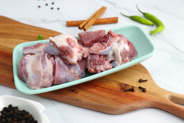 Fresh raw goat meat or mutton or lamb pieces. Preparation for Indian mutton curry. Spice at the background such as cinnamon sticks, red chili powder, black pepper & coriander. Copy space.