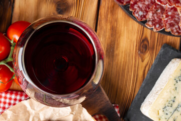 Wineglass with red wine and meat cuts board