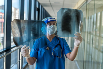 young nurse in a protective suit and face shield checking chest xray image, covid19