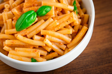 Healthy organic Italian macaroni homemade fresh pasta spaghetti noodles cook with basil tomato garlic pepper sauce with vegan vegetarian recipe in white bowl on wooden vintage table