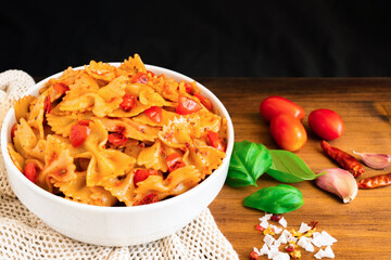 Healthy organic Italian Farfalle homemade fresh pasta spaghetti noodles cook with basil tomato garlic pepper sauce with vegan vegetarian recipe in white bowl on wooden vintage table